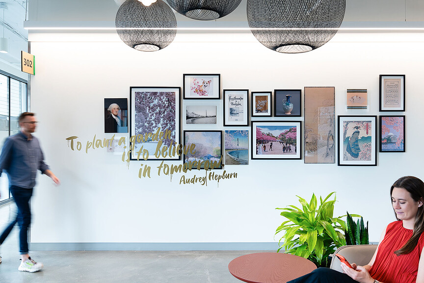A person sitting in a chair in front of a wall with pictures.